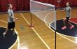 Two young teens volleying a shuttlecock over a multi-dome dual net set as a badminton net