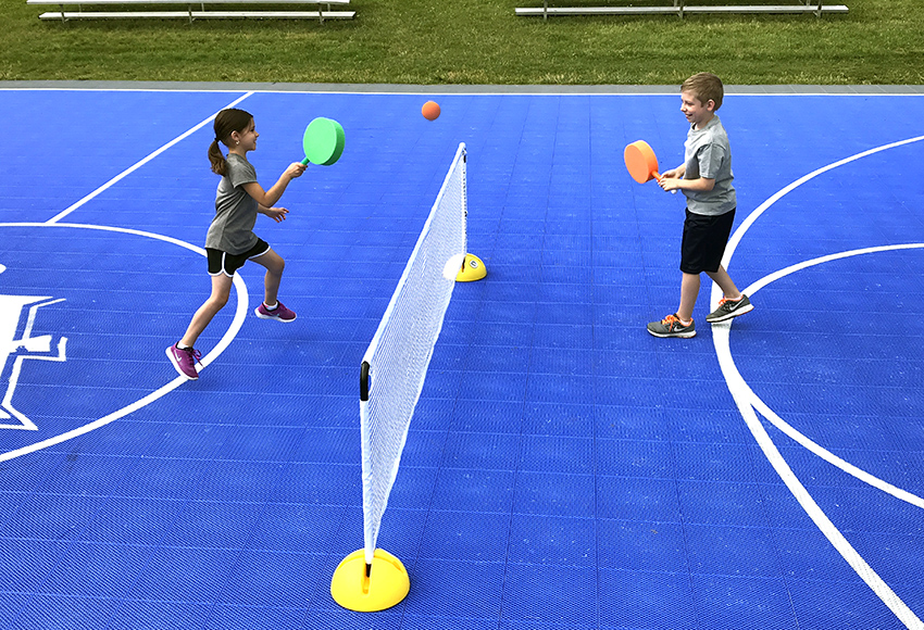 Two small children with foam lollipop paddles hitting a foam ball over a multi-dome tennis net